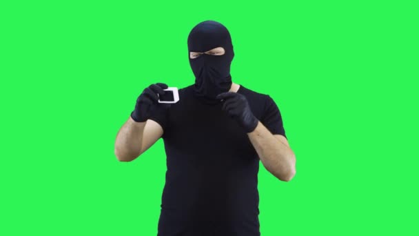 バラクラバの男が手に持っているアクションカメラで自分自身の写真を撮る、緑の画面の背景 — ストック動画