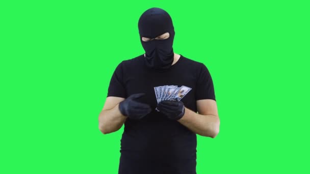 Zamaskowany człowiek trzyma pieniądze w rękach, liczy je i rzuca w dół.Balaclava.Green tle ekranu. — Wideo stockowe
