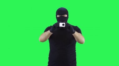 Kar maskeli bir adam elinde tuttuğu sırada kamerayı çıkartıyor, yeşil ekran arka plan.