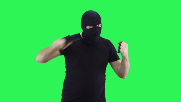 Ένας άνθρωπος σε μια μαύρη μάσκα κρατά ένα μαχαίρι και σιδερογροθιές στο χέρι του, επιθέσεις.Balaclava.Green φόντο οθόνη. — Αρχείο Βίντεο