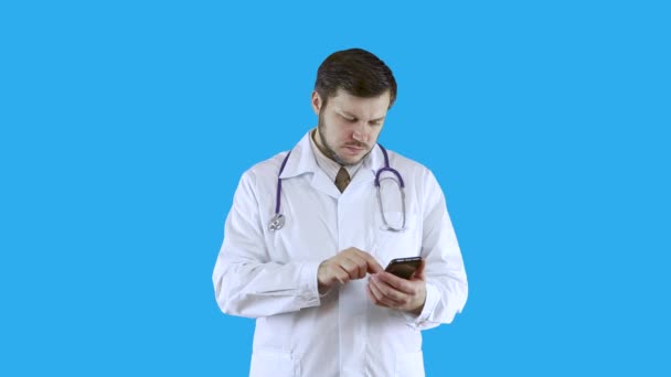 Trabajador médico con un abrigo médico blanco está surfeando por teléfono pensando en algo . — Vídeos de Stock
