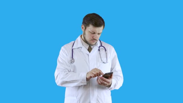 Dokter in een witte medische jas surft aan de telefoon.. — Stockvideo