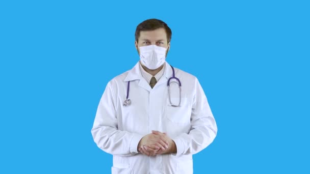 Een man in een witte medische jas en masker knikt met zijn hoofd. — Stockvideo