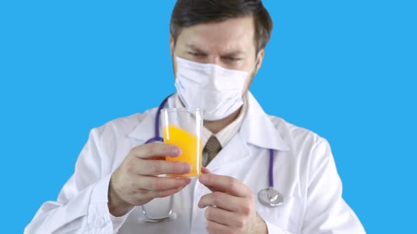 The doctor in a medical coat and mask holds in his hands a jar with tests. — Stock Video
