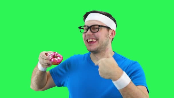 Atleta homem ansiosamente come um donut . — Vídeo de Stock