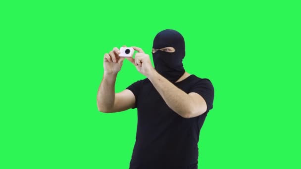 Een gemaskerde man maakt een actiecamera.Balaclava.Groen scherm achtergrond. — Stockvideo