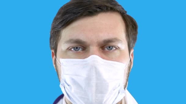 A doctor in a medical coat and mask is looking forward. — Stock Video