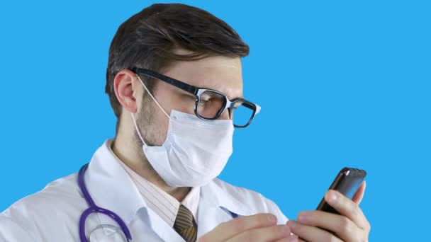 Un uomo con un camice medico sta navigando al telefono . — Video Stock