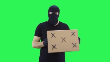 Siyah maskeli bir adam yeşil ekran arka planı için bir tabela tutuyor.