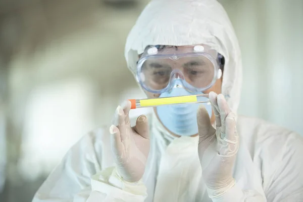 研究室内でコロナウイルスの検査結果を保持する保護具を身に着けている科学者 — ストック写真