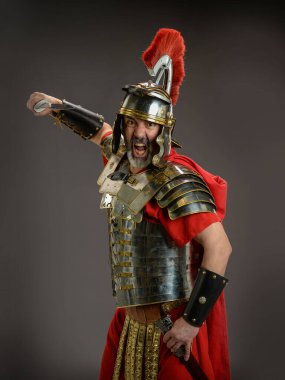 Roman soldier holding his sword ready to atack isoladed on a dark background clipart