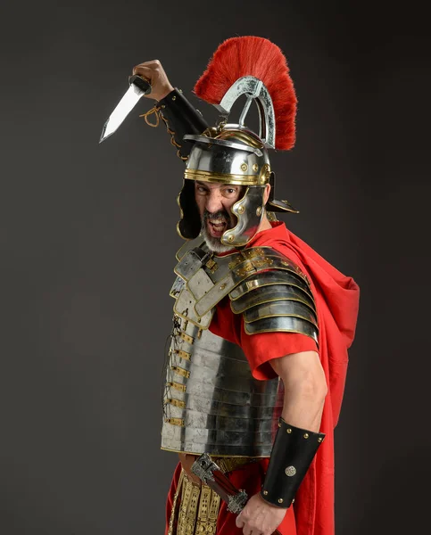 Roman soldier ready to strike with a sword isolated on a gray background