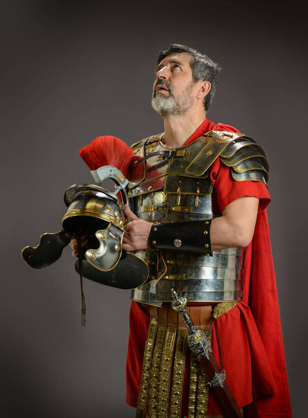 Roman soldier looking up and holding his helmet