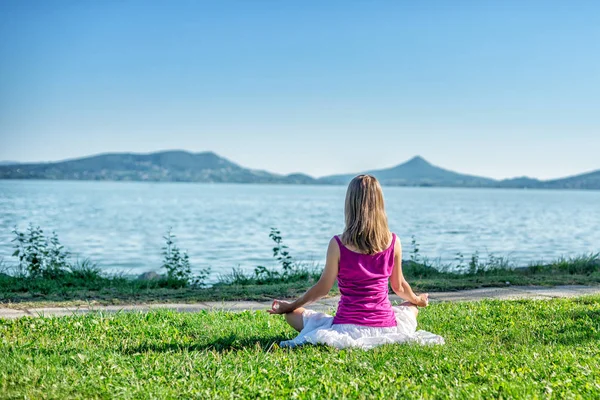 Mujer meditando en el lago — Foto de Stock