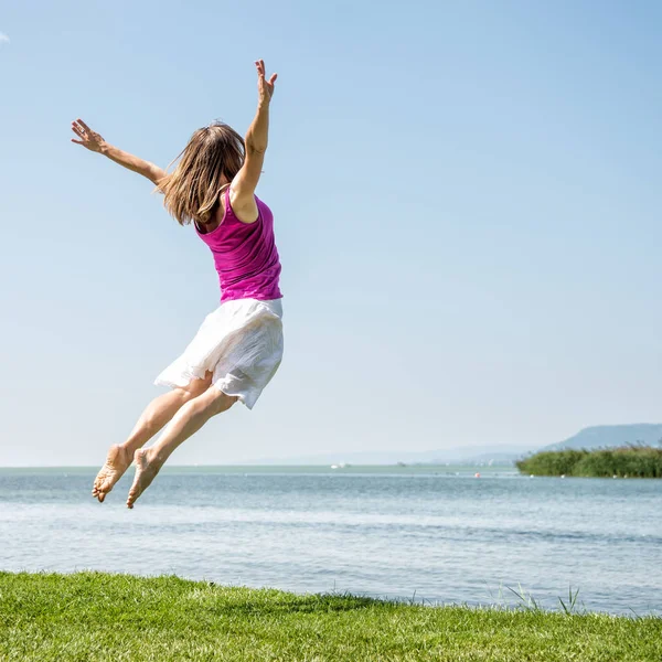 Meisje springen op het meer — Stockfoto