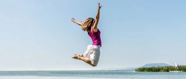 Fille sautant sur le lac — Photo