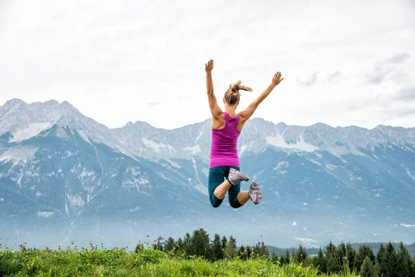 Jonge vrouw springen in de bergen — Stockfoto