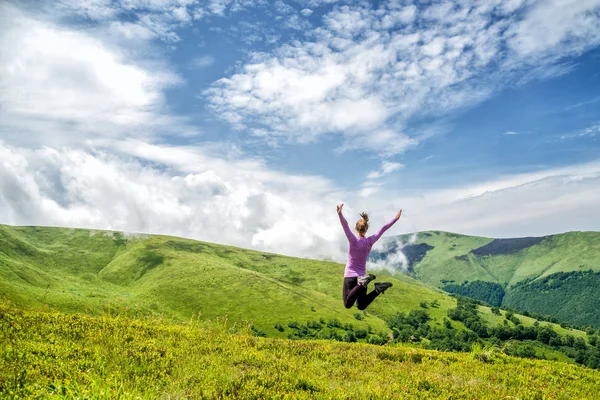 Junge Frau springt in die Berge — Stockfoto