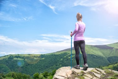 Dağlarda yürüyüş yapan genç bir kadın.