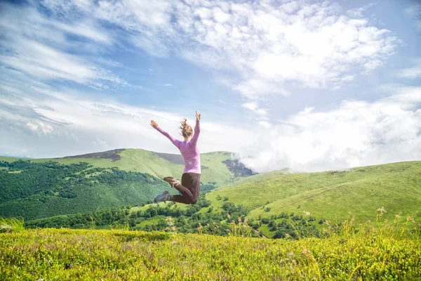 Mujer joven saltando en las montañas — Foto de Stock