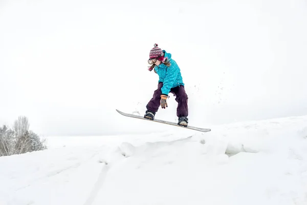 Jovem mulher no snowboard jumping — Fotografia de Stock