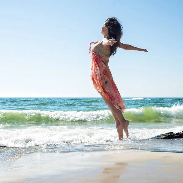 Молодая женщина прыгает на пляже — стоковое фото