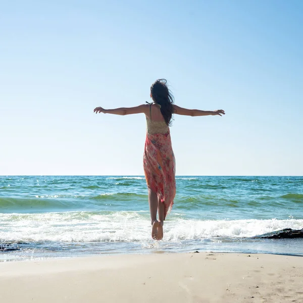 Młoda kobieta skacze po plaży — Zdjęcie stockowe