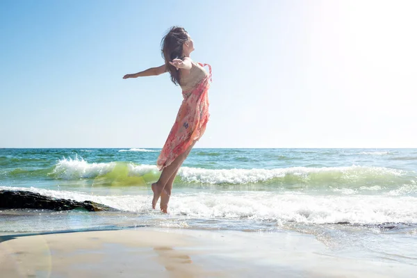 Młoda kobieta skacze po plaży — Zdjęcie stockowe