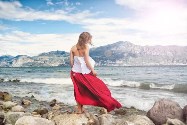 Mooi meisje in een rode jurk van de zee. — Stockfoto