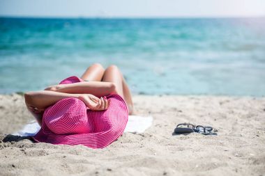 Sahilde rahatlatıcı şapkalı kadın