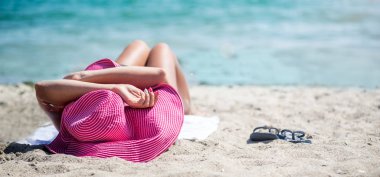 Sahilde rahatlatıcı şapkalı kadın