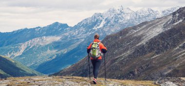 Dağlarda yürüyüş yapan genç bir kadın.