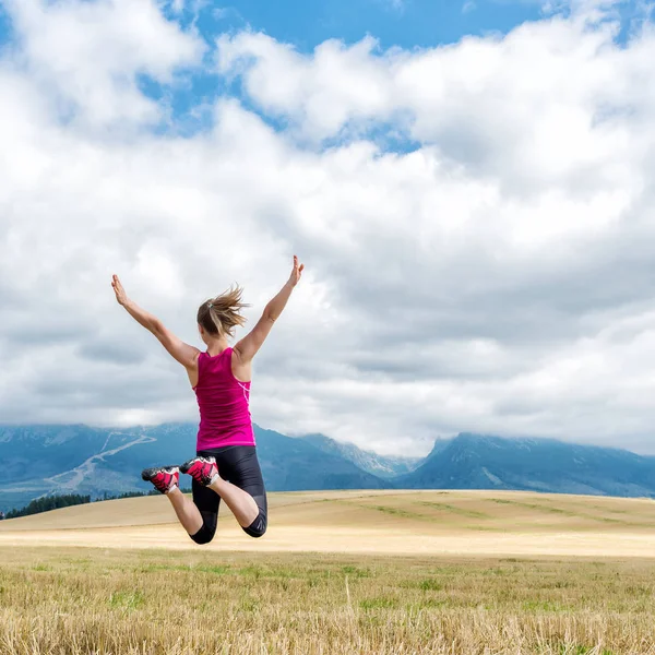 Jeune femme sautant dans les montagnes — Photo