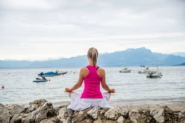 stock image Woman meditating at the lake