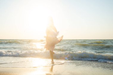 Beyaz bikinili genç bir kadın ve kumsalda siyah bir bikini. 