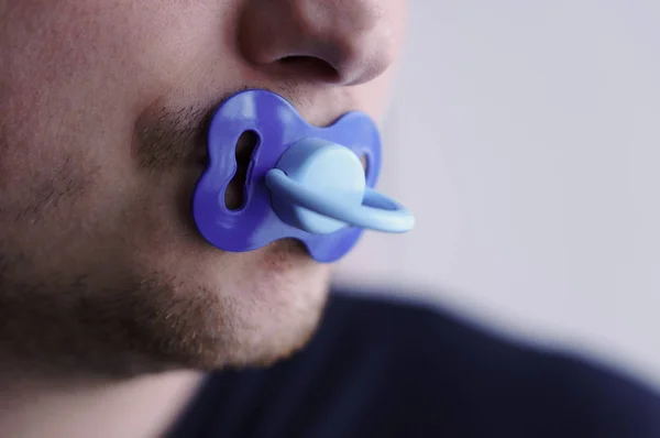 Een jonge man houdt een fopspeen in zijn mond — Stockfoto