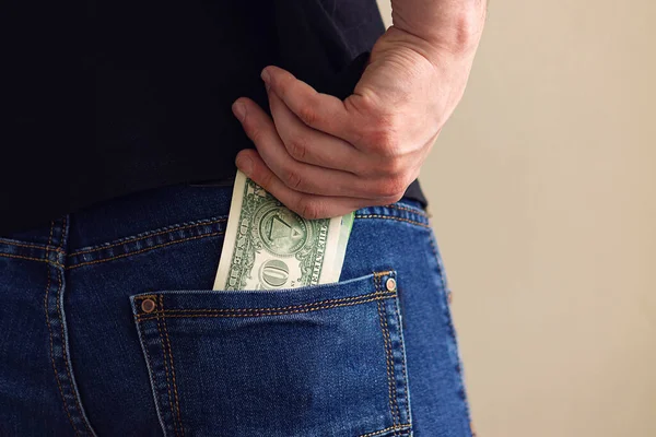 Adamın eli kotun arka cebinden dolar çekiyor.