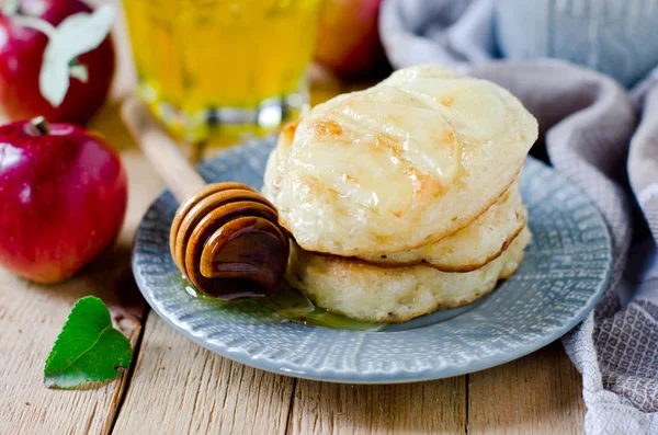 Apple yeast pancakes with honey on a plate on a wooden table — Stock Photo, Image