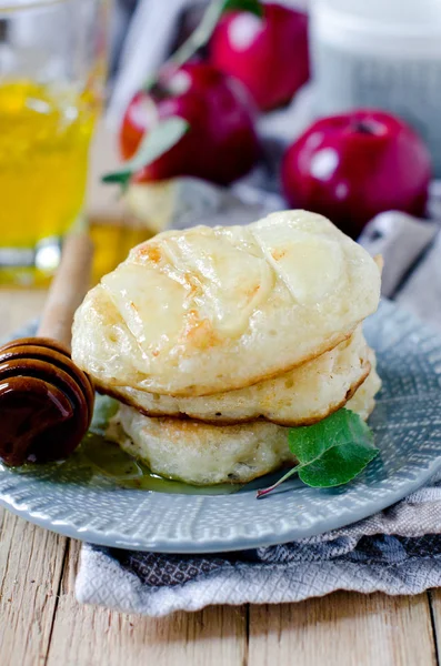 Яблочные блинчики с медом на тарелке на деревянном столе — стоковое фото