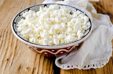 Ahşap bir masada, bir kasede süzme peynir.