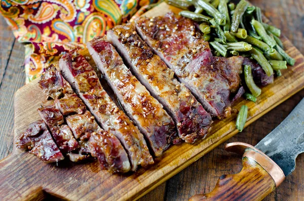 Pork steak with green beans on a wooden table — Stock Photo, Image