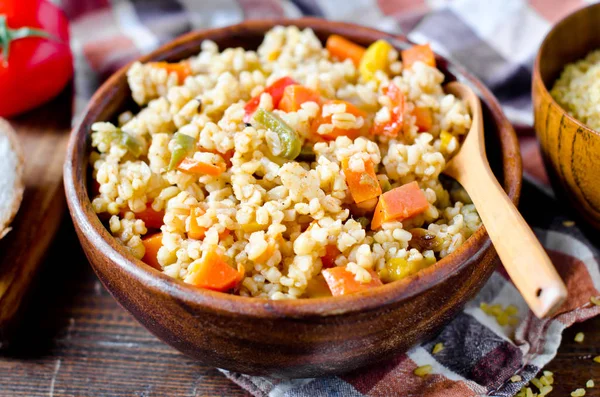 Porridge from bulgur with vegetables: carrots, bell peppers, oni — Stock Photo, Image