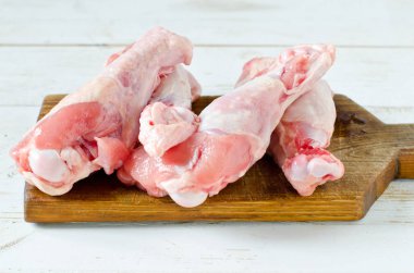 Çiğ çiğ tavuk budu, sopaları ahşap tahta, etli üzerinde