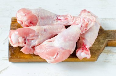 Çiğ çiğ tavuk budu, sopaları ahşap tahta, etli üzerinde