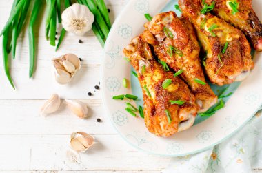 Beyaz ahşap bir masa üzerinde bir tabakta tavuk budu pişmiş