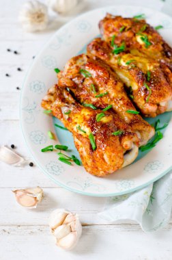 Beyaz ahşap bir masa üzerinde bir tabakta tavuk budu pişmiş