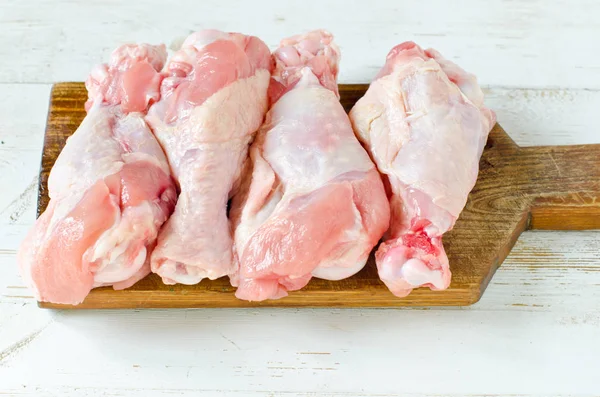 Raw uncooked chicken legs, drumsticks on wooden board, meat with — Stock Photo, Image
