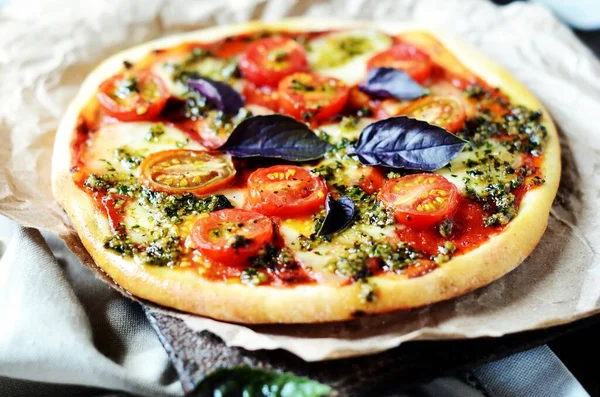 Pizza margarita with pesto on a dark wooden background. rustic