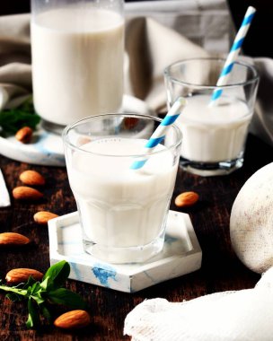 Arkaplanda cam bardaklarda badem sütü.