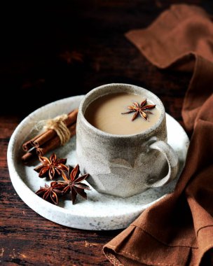 Koyu ahşap arka planda, baharatlı seramik bardakta Masala çayı.